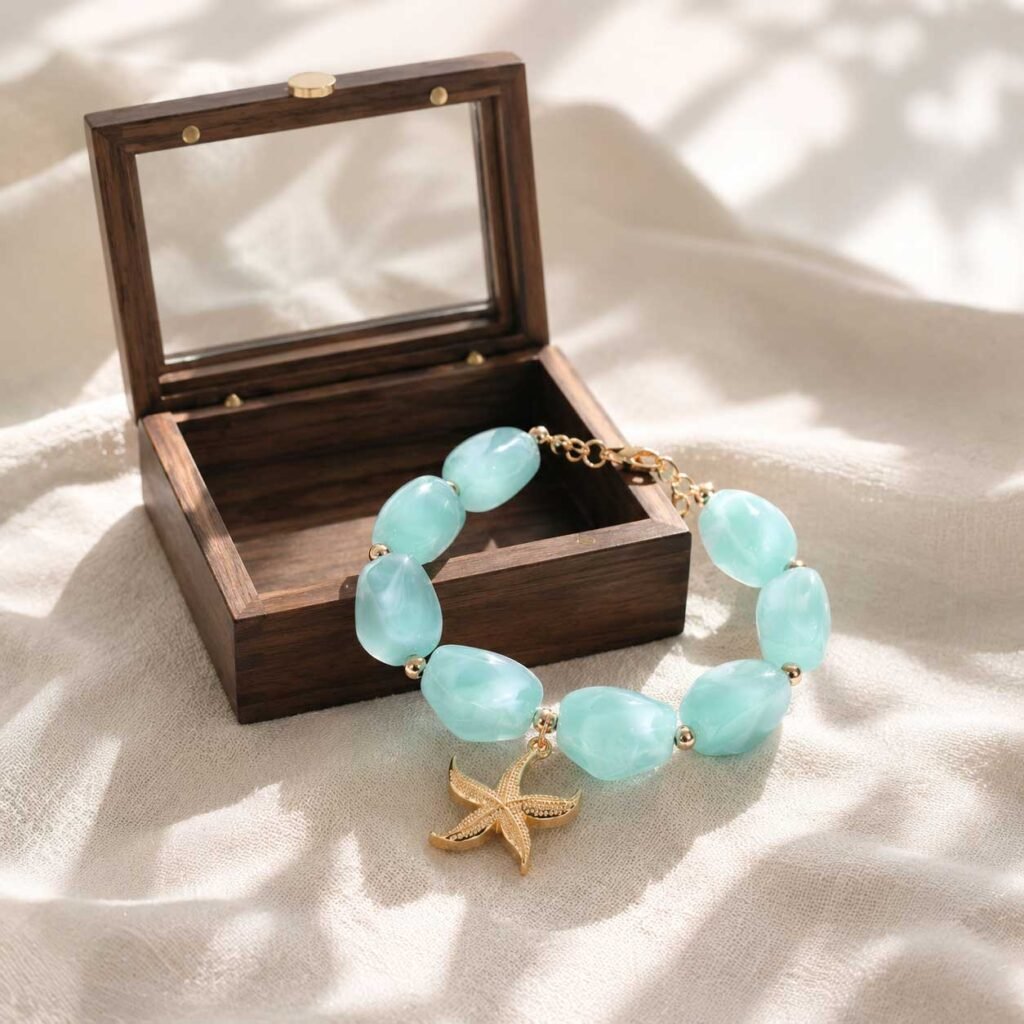 A close-up of a curated lucky charm bracelet featuring clear translucent resin beads and a sleek starfish charm, nestled safely inside a simple natural wooden box under gentle morning natural light.