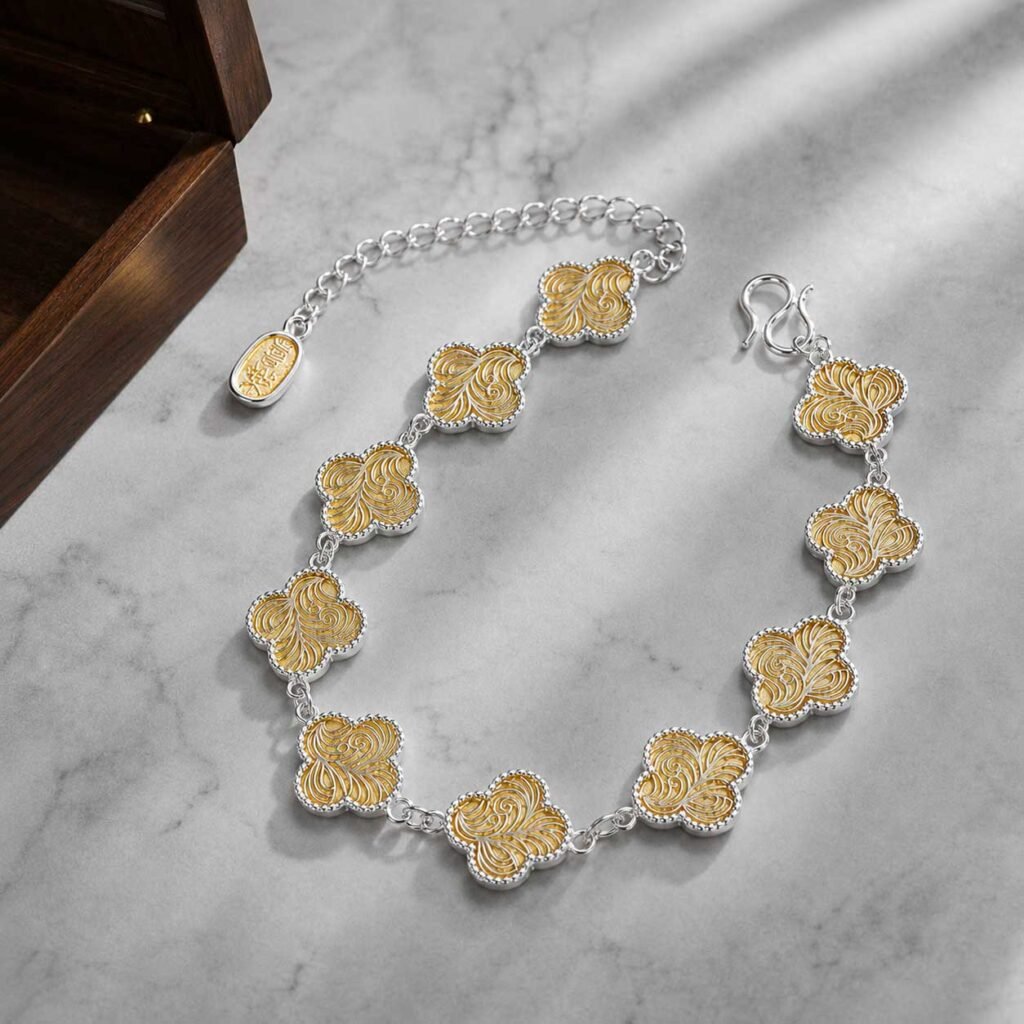 Close-up of a premium handcrafted good fortune charm bracelet made of silver-plated cupronickel links with detailed four-leaf clover charms, 24h sound-bath calibrated at 528Hz, displayed elegantly inside the signature white Luxe Abundance Box.