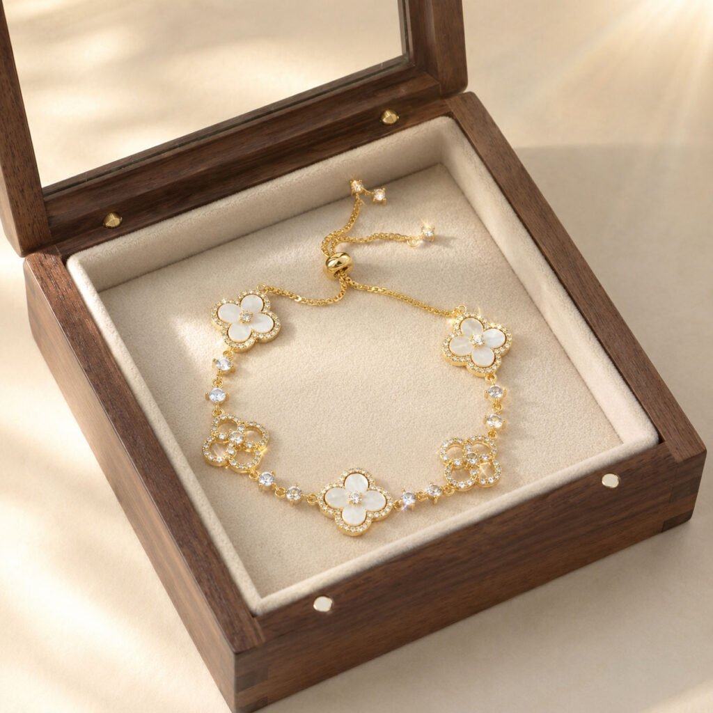 Close-up of a red four-leaf clover bracelet in a gold-tone setting, styled as meaningful quiet-luxury jewelry in the white Luxe Abundance Box.