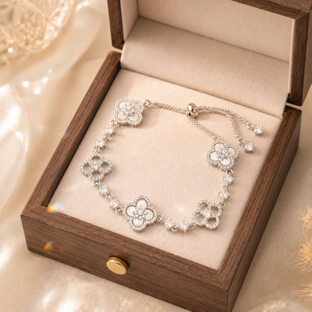 Close-up of a white clover mother-of-pearl bracelet with iridescent shell petals in a polished setting, presented in the white Luxe Abundance Box.