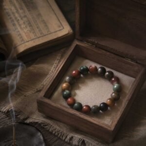 Close-up of a curated oriental incense bead bracelet with antique textures, resting peacefully inside a simple natural wooden box under gentle mountain light.